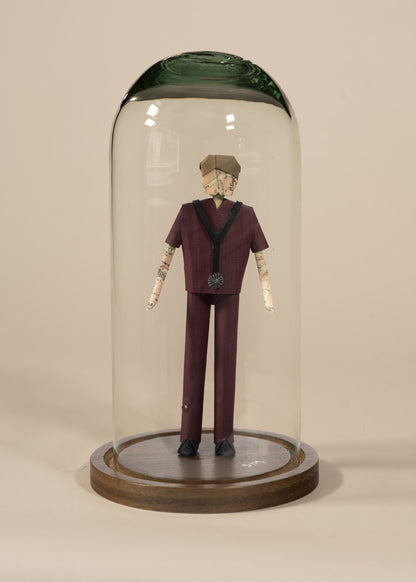 Doctor de origami con scrubs color vino, en capelo de vidrio sobre base de madera
