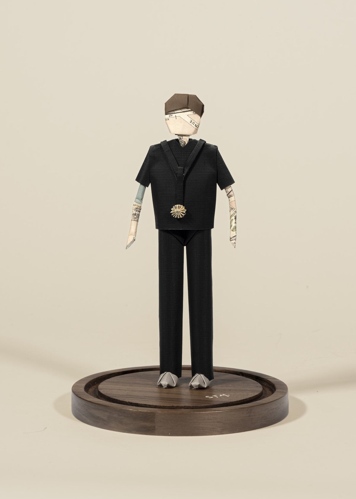 Figura de doctor de origami con scrubs negros, sobre base de madera