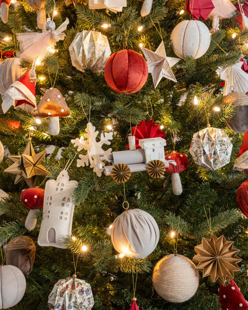 Esfera tren de origami en gris colgada en el árbol de Navidad, entre esferas de terciopelo y papel