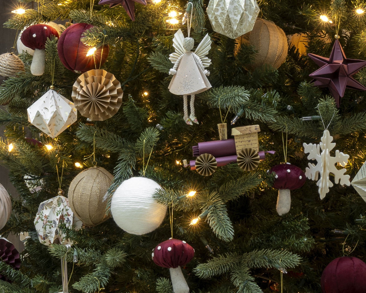 Ángel hada colgada en el árbol de Navidad, entre esferas de papel y lana