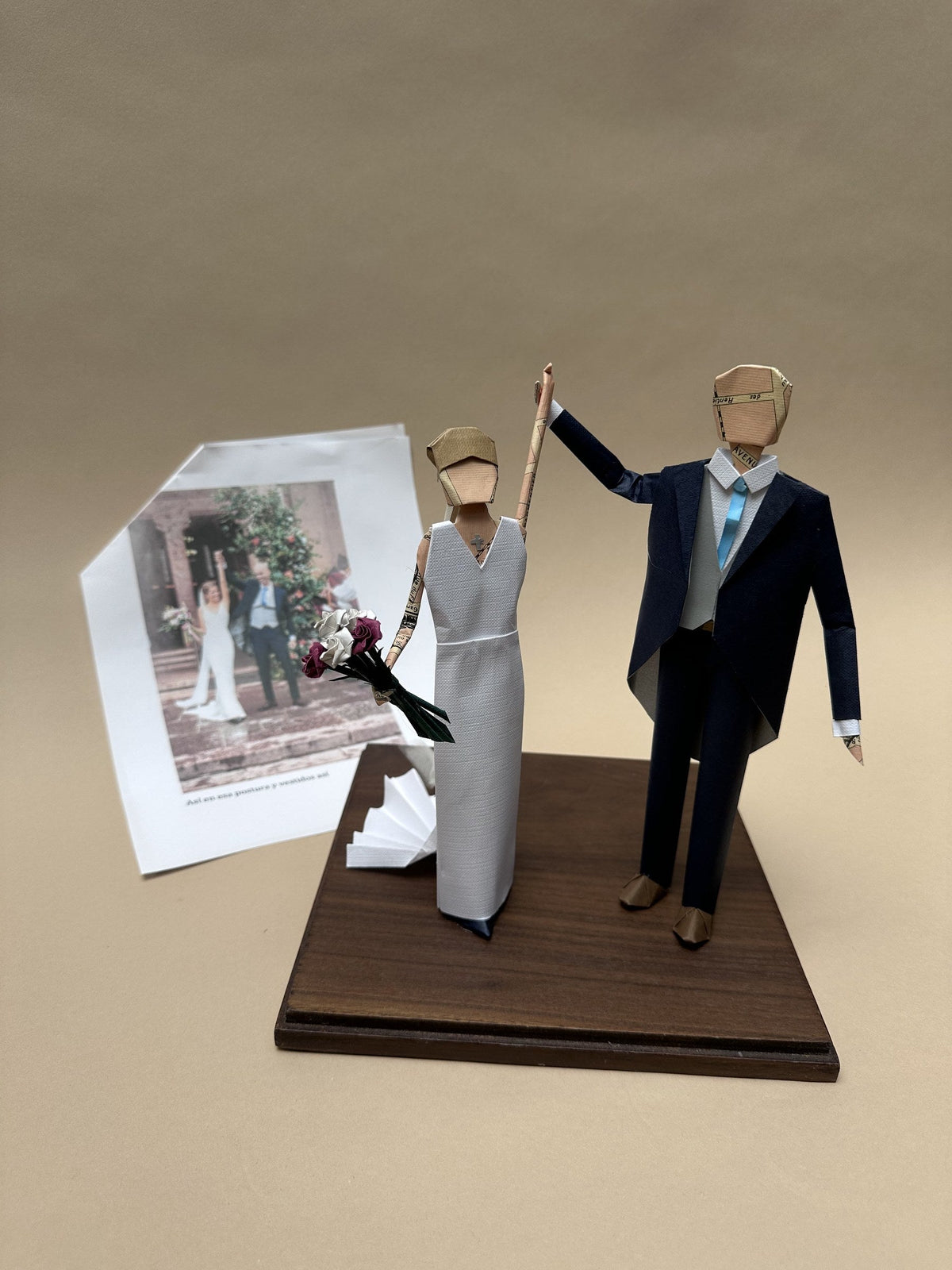 Pareja de novios de papel hecha a partir de su foto, sobre base de madera, junto a la foto de referencia