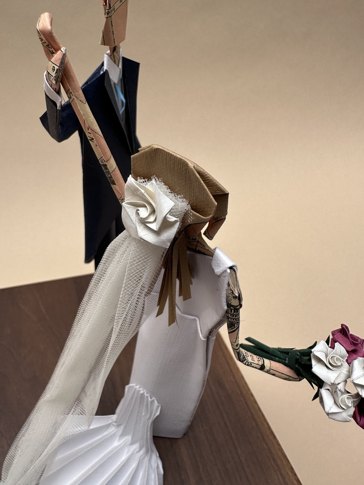 Detalle de la novia de papel: vestido plisado, velo de tul y ramo de flores de origami