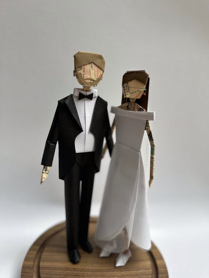 Novios de papel de cerca: esmoquin con moño y vestido blanco con detalle dorado