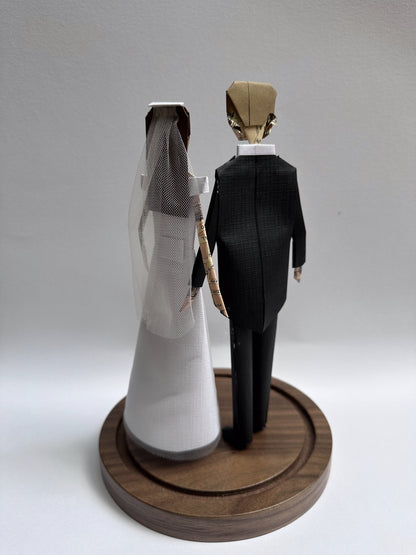 Novios de papel vistos de espalda, con el velo de la novia y el frac del novio