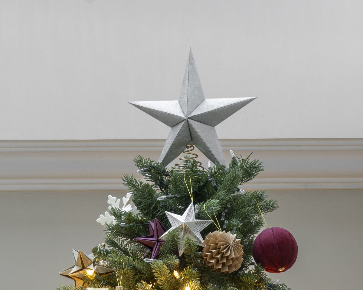 Punta de árbol estrella plateada colocada en la punta de un árbol de Navidad