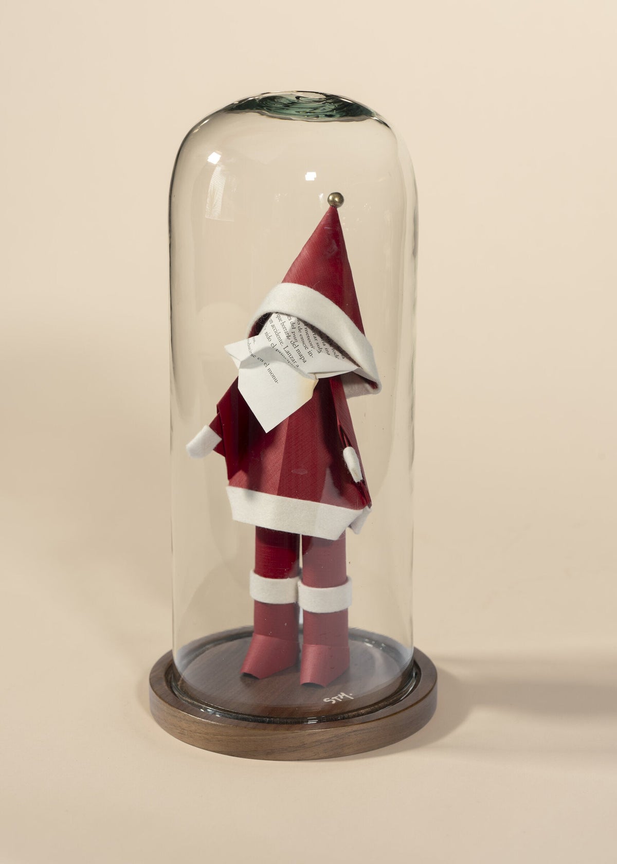 Santa de origami en rojo, dentro de capelo de vidrio sobre base de madera