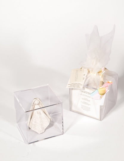 Virgen de origami para bolo en caja de acrílico, junto al bolo ya envuelto con papel de seda y tarjeta