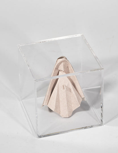 Virgen de origami en papel tapiz rosa, dentro de caja de acrílico, vista de tres cuartos