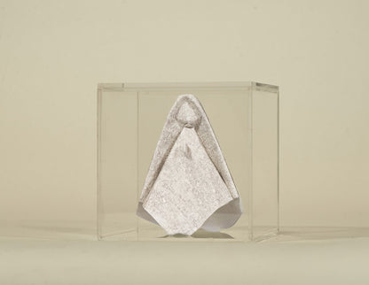 Virgen de origami en papel tapiz claro, dentro de su caja de acrílico